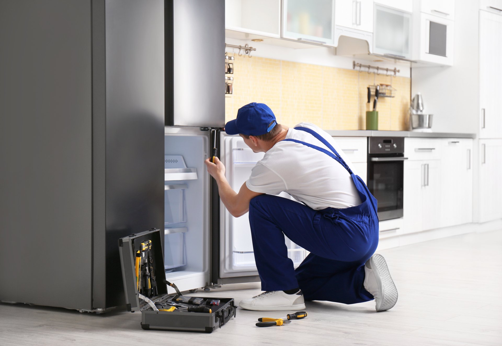 a technician repairing a refrigerator - Appliance Repair Roswell Pros